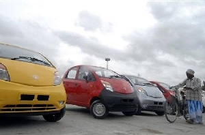 Một người đàn ông Ấn Độ dắt chiếc xe đạp ngang qua dãy xe Tata Nano, loại xe nhỏ có giá 2.500 USD - tinhkinhte.com